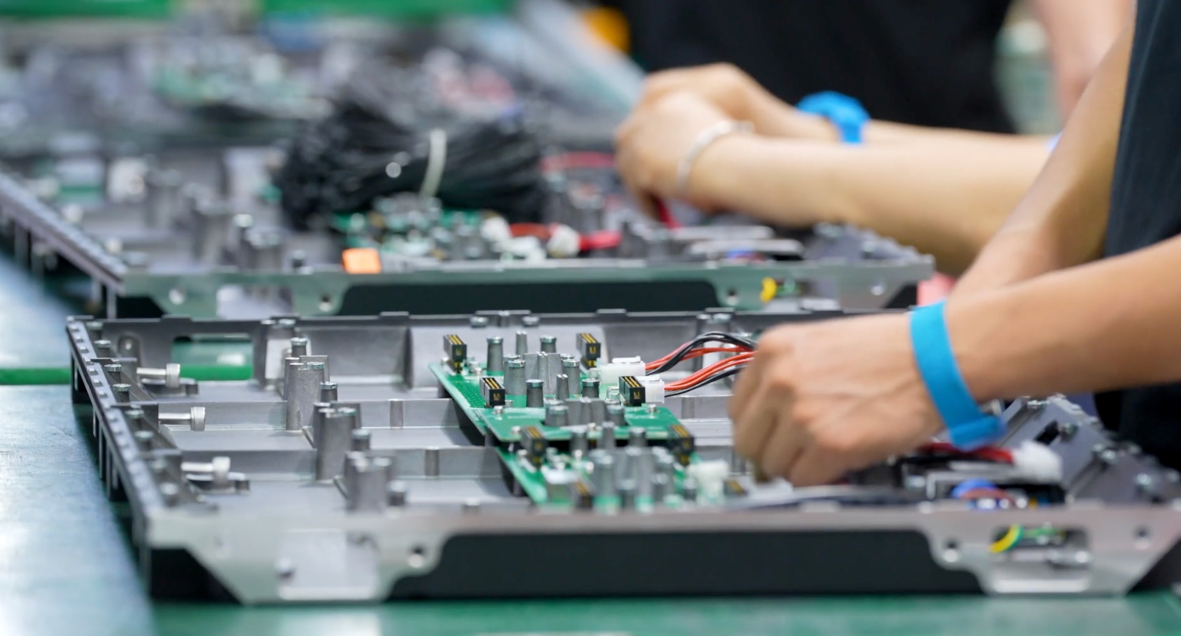 Technicians assembling Altitude LED panel circuit boards at a factory workbench