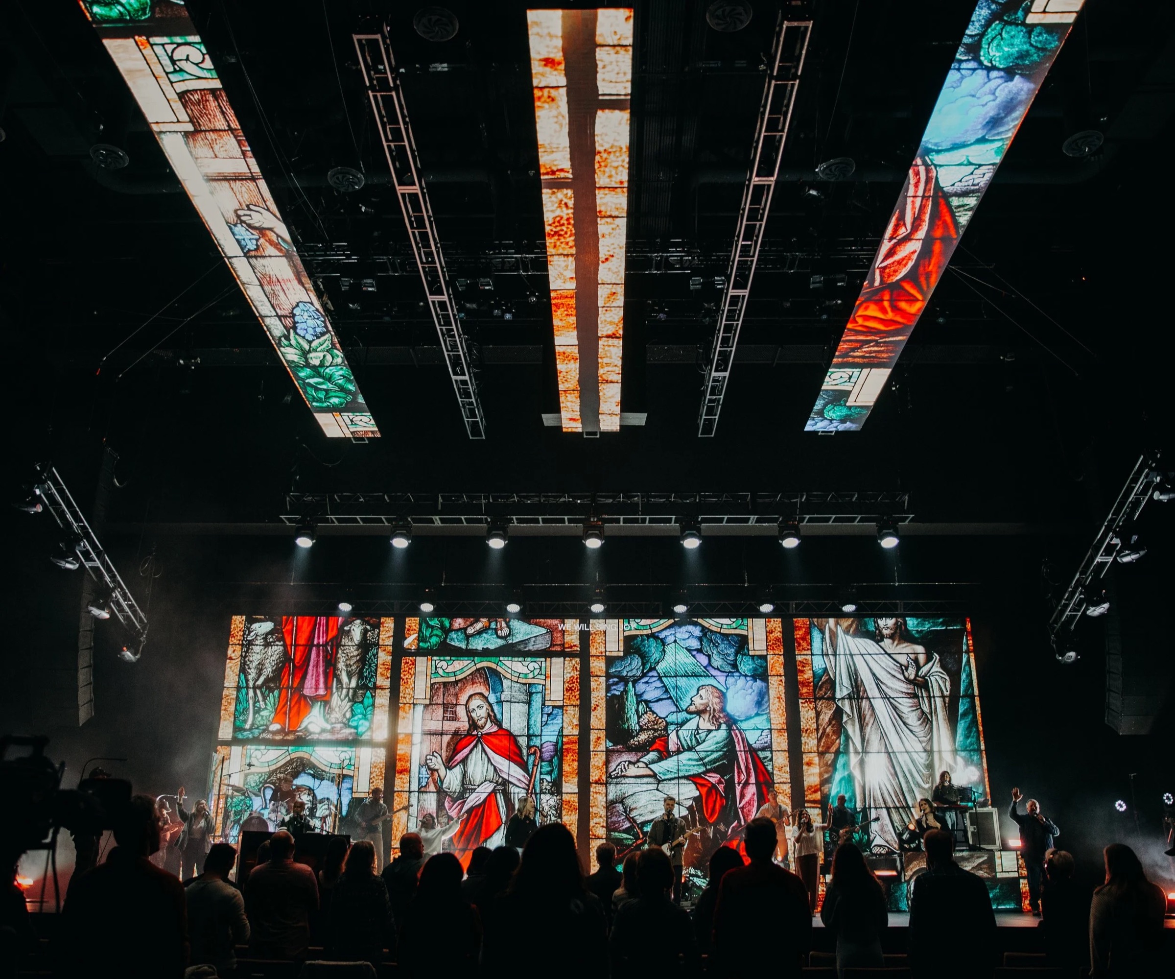 Worship stage with vertical LED ceiling panels and LED walls showing stained glass visuals